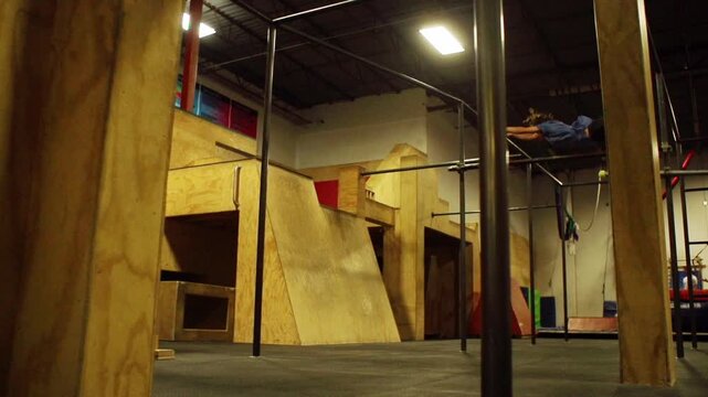 A young sportsman performing stunts and flips on parallel bars in a gym