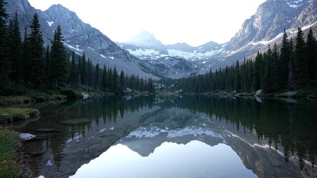 Serene mountain lake surrounded by evergreen trees and snow-capped peaks in peaceful natural setting video