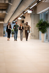 Diverse business team walking office corridor during coffee break