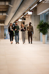 Fototapeta premium Diverse business team walking through office hallway during coffee break