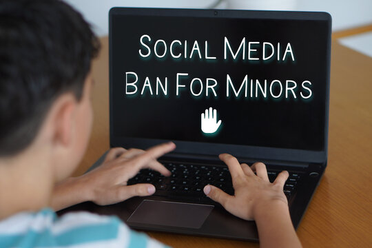 social media ban for minors. Digital safety and well-being in childhood and adolescence. Child typing on their laptop