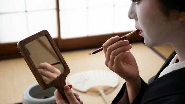 Traditional geisha applying lipstick with brush while looking in hand mirror, Japanese culture and beauty ritual.