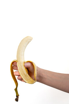 Close-up of a peeled banana held in a human hand. Minimalistic composition with natural light, symbolizing healthy eating, nutrition, freshness, and simplicity. Concept of diet, vegan lifestyle, potas