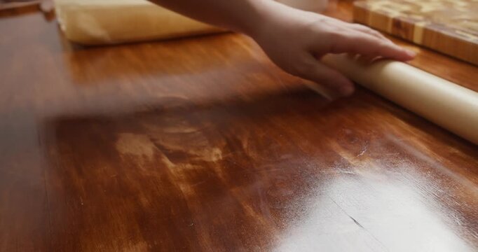Woman wraps salmon fillet seasoned with salt and pepper in parchment paper for curing. Close-up of homemade salmon preparation process in kitchen, traditional food preservation and cooking at home.