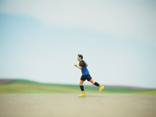 Obraz premium Mini toy of action figure at table with blurred background. Miniature photography concept. Runner at outdoor conceptual design. Young man running at outdoor.