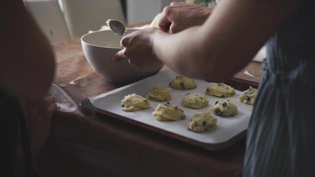 Mother baking cookies at home with her daughters watching the process, focusing on the tactile process of homemade baking and warm family interaction concept