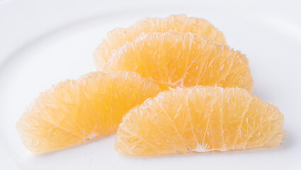 Fruit slices are arranged on a white plate. The segments are juicy and ready to eat. This serves as a refreshing snack or dessert option