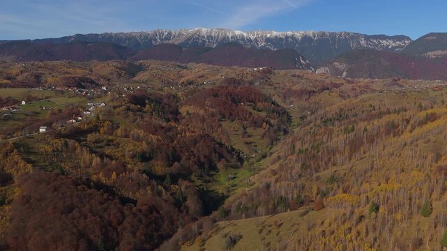 Stunning Autumn Pestera Village Scattered Houses under Piatra Craiului Mountains Aerial Forward Ascending Shot 4K Graded