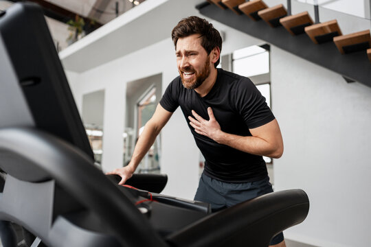 Man experiencing severe chest pain and medical emergency during treadmill exercise in gym