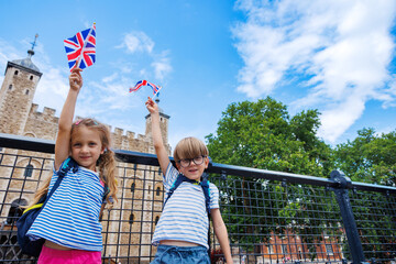 Happy tourists kids waving British flags at historic castle site