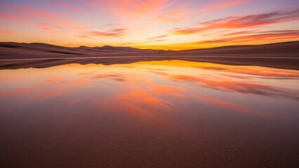 Fototapeta premium Vibrant sunset sky reflecting on still water in a serene desert landscape with distant dunes