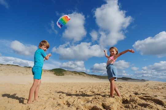 Kids holding together a colorful kite parachute on the beach