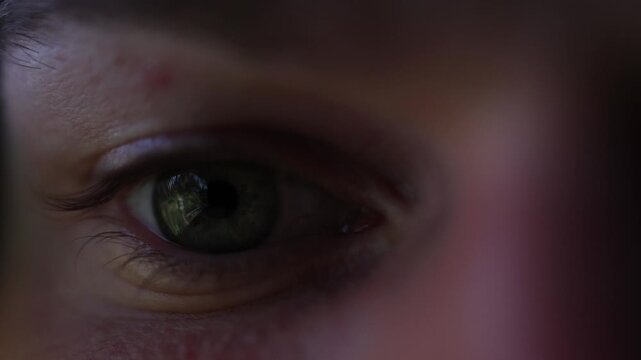 Close up of student eye illuminated by monitor light computer game reflected in pupil long hours of gaming replacing study time and showing digital distraction
