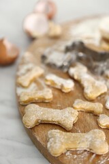 Homemade dog treats. Raw bone shaped cookies and cookie cutter on white wooden table, closeup