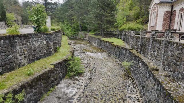 Mountain stream flowing beside Bele Vode church near Mokra Gora in spring. Scenic rural Serbia landscape combining nature, architecture and spiritual heritage tourism