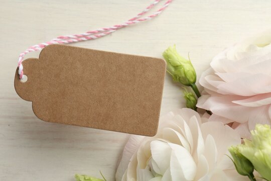 Beautiful flowers with blank card on white wooden table, closeup. Mockup for design