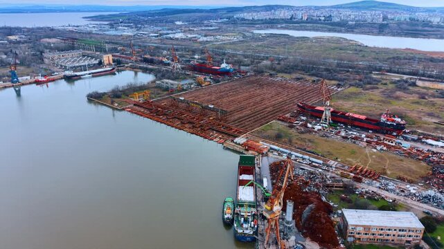 Industrial shipyard landscape with cargo ship and metal storage. Elevated view of a shipyard featuring ship repair zones, metal structures, and a cargo ship being loaded.