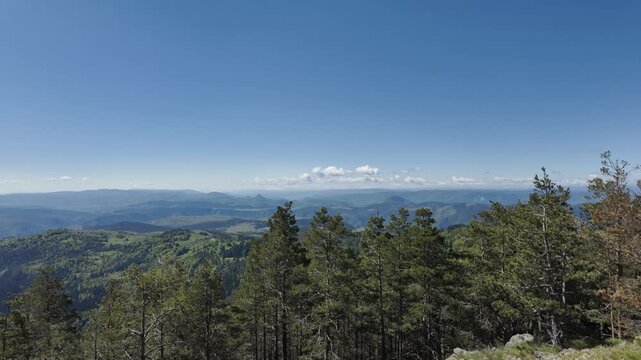 Panoramic view from Tornik mountain over forest and rolling hills in Zlatibor region during spring. Scenic natural landscape with clear sky and vast valley horizon in Serbia