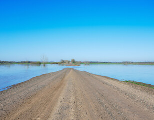 Road flooded and cut off with water crossing asphalt in rural area