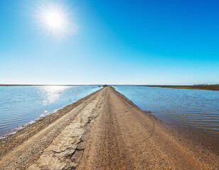Road flooded and cut off with water crossing asphalt in rural area
