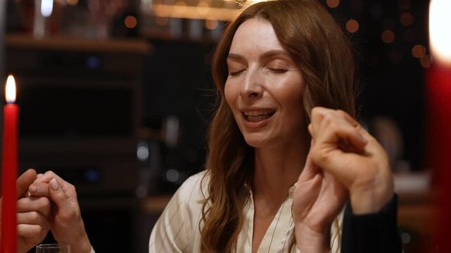 Woman holding hands with eyes closed and saying a prayer while sitting and laughing