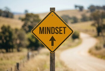 Yellow directional sign indicating mindset with arrow pointing towards growth and positivity on a tranquil country road surrounded by greenery and trees