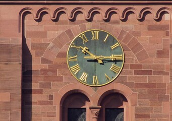 Fototapeta premium Close-up of the historic clock with Roman numerals on Johanneskirche church facade in Freiburg im Breisgau, Germany. Red brick Gothic Revival architecture detail, 25 March 2011
