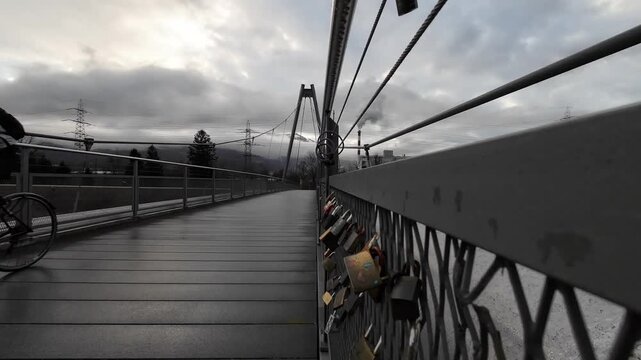 Static shot of cyclist approaching camera while riding across bridge with love locks, active lifestyle concept
