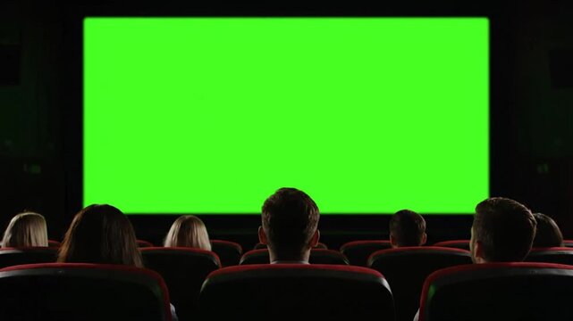 Cinema audience watching green screen movie in dark theater with cinematic lighting for film production