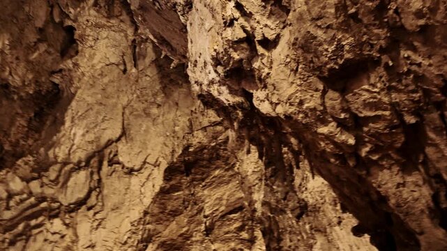 Panoramic view of textured limestone walls inside Stopica Cave in Zlatibor. Detailed rock formations illuminated by warm light reveal natural geological patterns in the Serbian underground