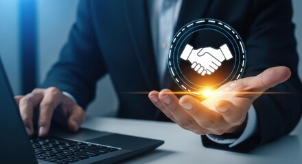 A businessman in a suit holding a glowing handshake icon above his palm with a laptop in front of him