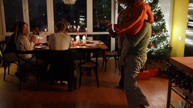 Granddaughter leads grandpa and grandma and he lifts her in his arms and they dance while their family and guests sit at the table