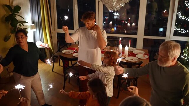 Family and guests dance while a woman gives them sparklers
