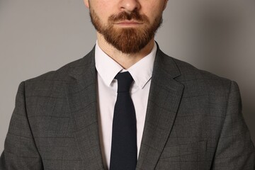 Bearded businessman in suit on grey background, closeup