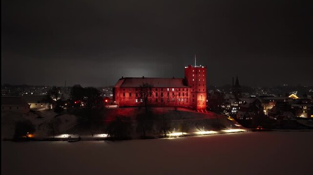 Historic Koldinghus castle glowing red at night, cinematic drone footage