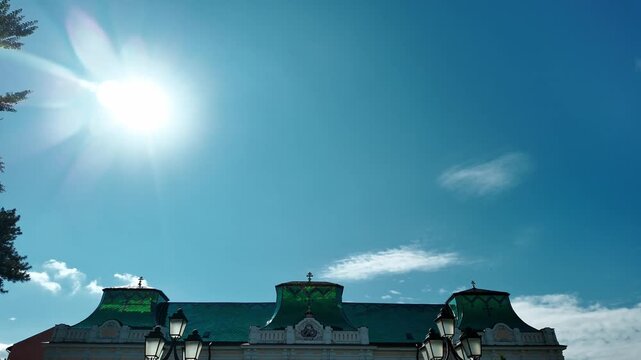 Vladicanski dvor with its distinctive green roof and symmetrical facade. Historic bishop palace surrounded by garden, trees and classic street lamps on a sunny day.