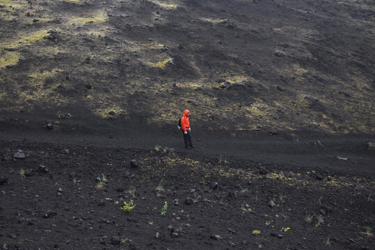 This is a path between slag. There is a man on the foreground. There is a slag slope on the background.