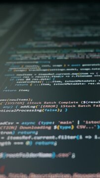 Computer programming code scrolls vertically on a dark monitor screen with colorful syntax. Concept represents the flow of vibe coding where AI assists in zero code generation.