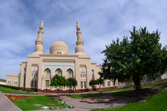 Exterior view of the landmark Jumeirah Mosque in Dubai featuring traditional Fatimid-style architecture with white stone and two towering minarets.