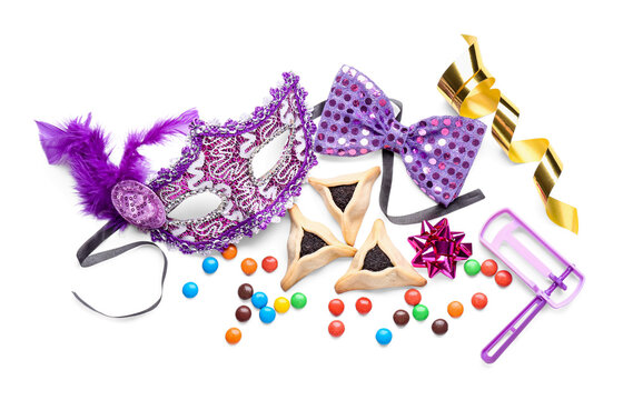 Festival mask, rattle, candies and tasty hamantaschen on white background. Purim celebration