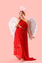 Naklejka premium Beautiful woman dressed as Cupid on pink background. Valentine's Day celebration