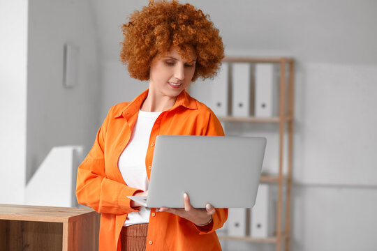 Young female programmer with laptop in light office