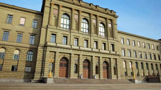 Panning shot of the historic ETH Zurich main building facade, showcasing the neoclassical architecture of the renowned Swiss Federal Institute of Technology under a clear blue sky.
