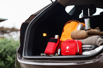 Emergency backpack, first aid kit and necessities in trunk of car outdoors, closeup