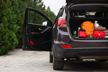 Emergency backpack, first aid kit and necessities in trunk of car outdoors © Pixel-Shot