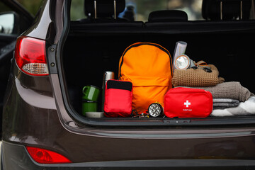 Emergency backpack, first aid kit and necessities in trunk of car outdoors, closeup