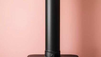 Obraz premium The black flue pipe serves as an exhaust for the wood stove and rests on a pale pink wall