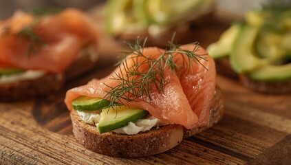 Open-faced sandwiches with toasted bread, smoked salmon, cream cheese, sliced cucumber, dill, and avocado on a wooden cutting board, close-up view
