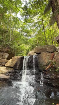 Small waterfall flowing through a lush green forest. Concept of nature escape, tranquility, mental wellness, slow living, eco travel, digital detox, relaxation and peaceful outdoor retreat.