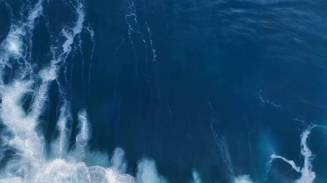 Top down aerial view of deep blue ocean waves crashing and creating white sea foam